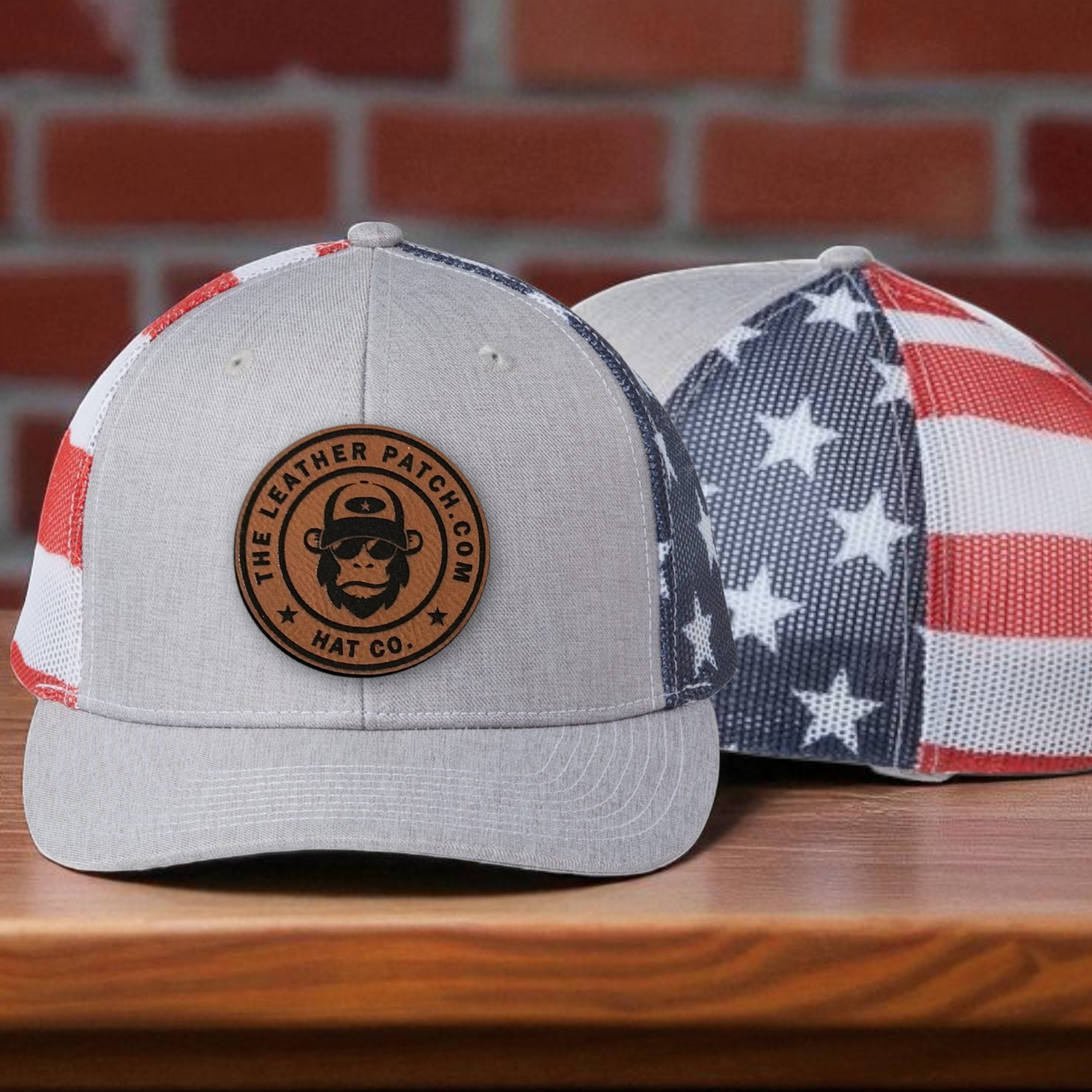 two baseball caps on a wooden surface, one with an American flag pattern and the other with a circular logo.