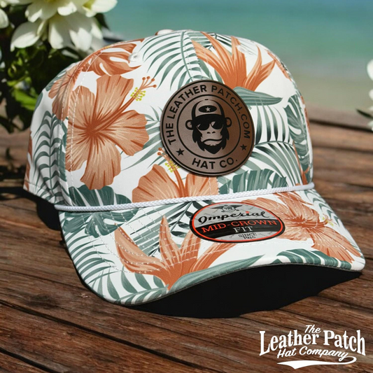 A white baseball cap with a tropical print pattern, featuring a circular patch with a monkey wearing sunglasses and the text "The Leather Patch Hat Company".