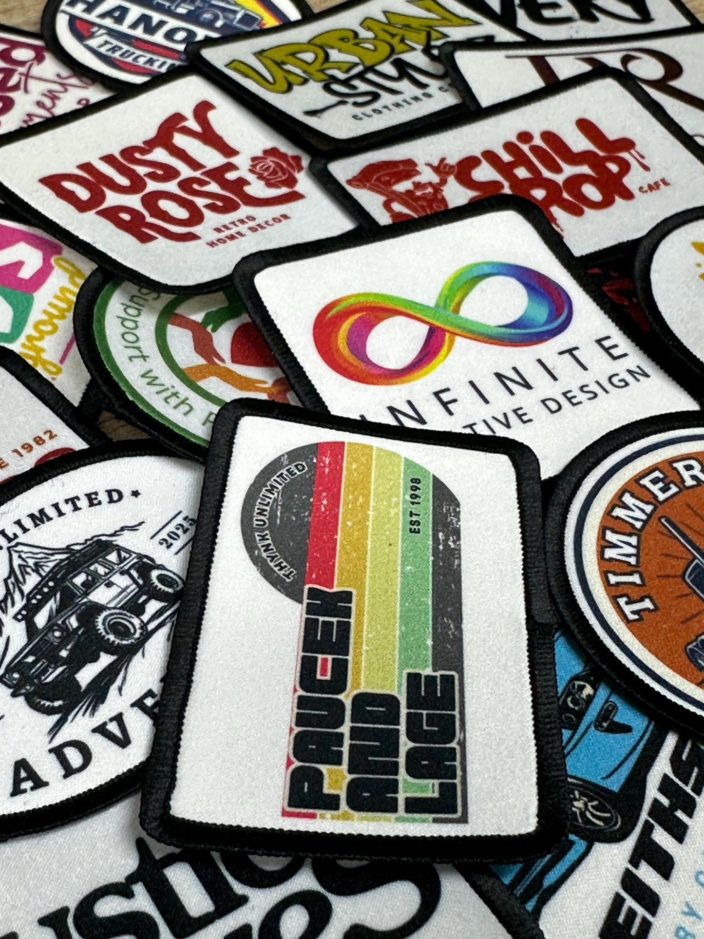a collection of various patches or logos, including a patch with a rainbow-colored design and the text &quot;Infinite Design&quot;.